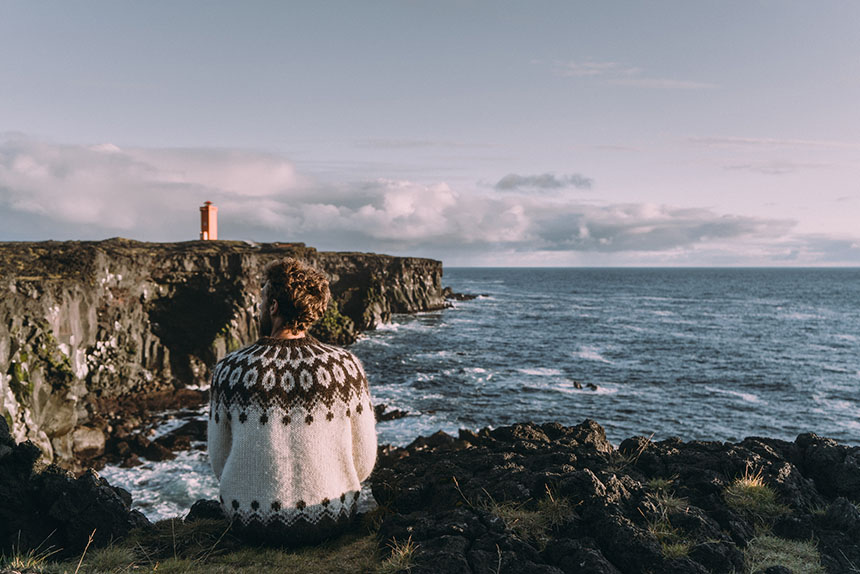 Tourist wearing an Icelandic jumper overlooking the coast